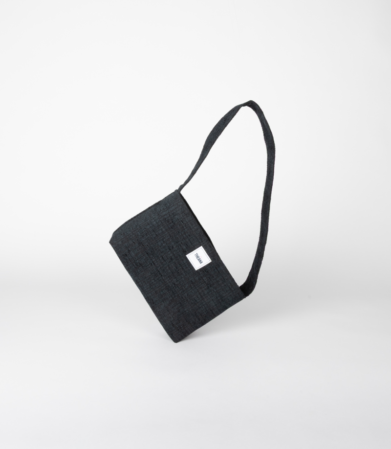 mini sac noir texturé avec reflets bleus posé sur le côté – marque Theana