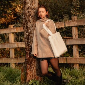 tote bag beige en tissu bouclette porté à l’épaule – marque THEANA